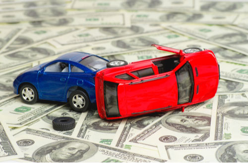 Toy cars crashed on top of money, car accident claim concept