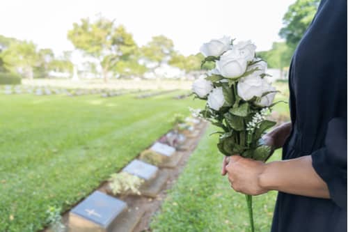 Woman holding roses at grave, Gwinnett wrongful death lawyer concept