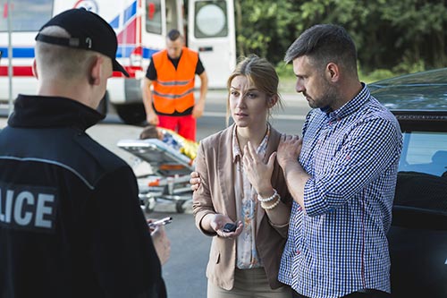 A police officer asking witnesses about a car car crash